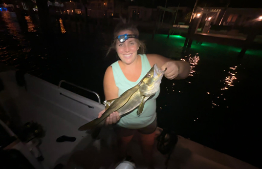 Woman holding a fish in the dark on an all day inshore fishing charter
